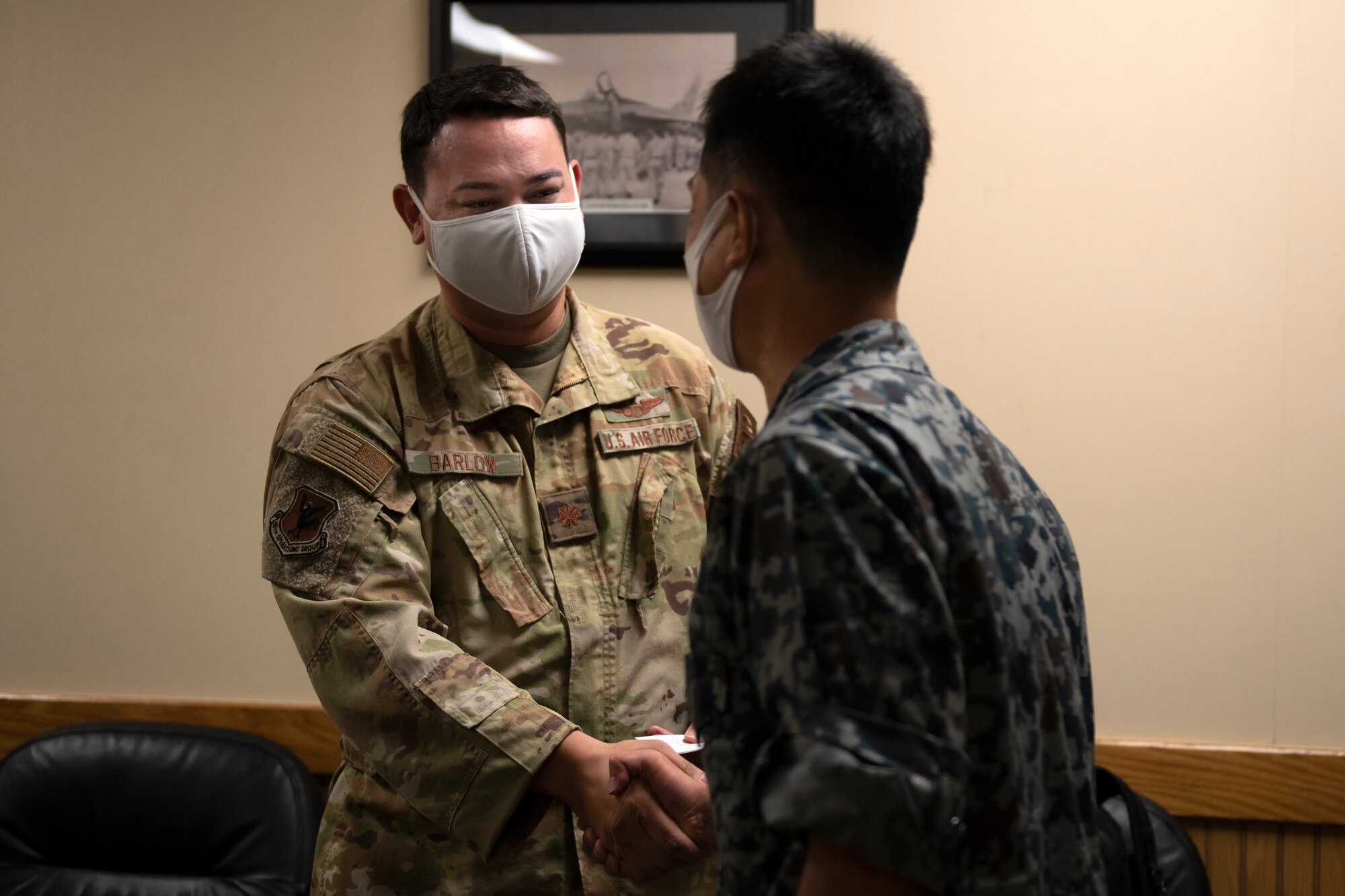 U.S. Air Force Maj. Logan Barlow, 18th Operations Group director of staff, shakes hands with Japan Air Self-Defense Force Lt. Col. Sunao Matsumoto, 9th Air Wing base supply commander, after a multi-capable Airman briefing at Kadena Air Base, Japan, Nov. 10, 2021. Sharing practices and training tools strengthens relations between U.S. forces and host nation allies, creating a more effective bilateral partnership. (U.S. Air Force photo by Senior Airman Jessi Monte)