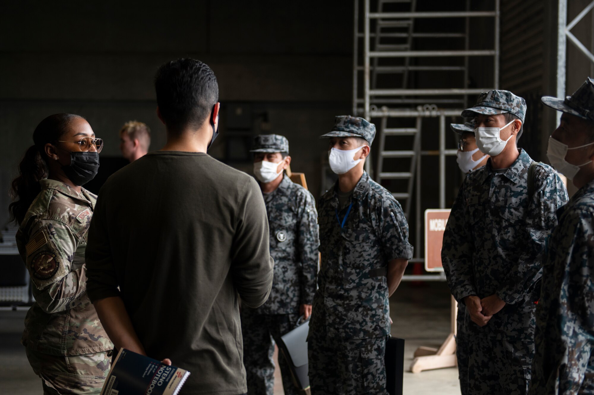 U.S. Air Force Master Sgt. Jakeis Robertson, 18th Logistics Readiness Squadron individual protective equipment section chief, briefs Japan Air Self-Defense Force members during a tour of the 18th LRS mobility processing building at Kadena Air Base, Japan, Nov. 10, 2021. Sharing practices and training tools strengthens relations between U.S. forces and host nation allies, creating a more effective bilateral partnership. (U.S. Air Force photo by Senior Airman Jessi Monte)