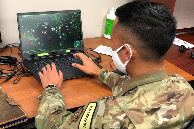 An airman works on a laptop.