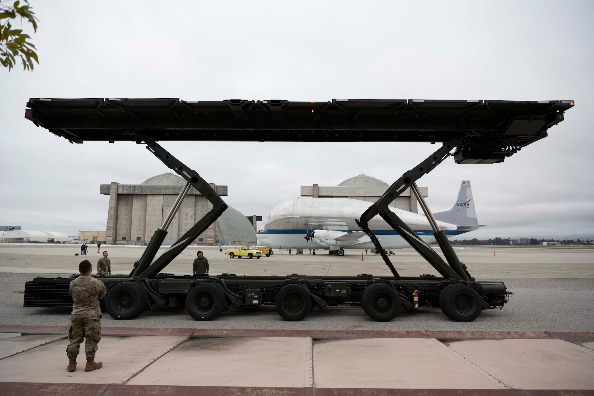 Airmen stand around a vehicle with an airplane behind them.