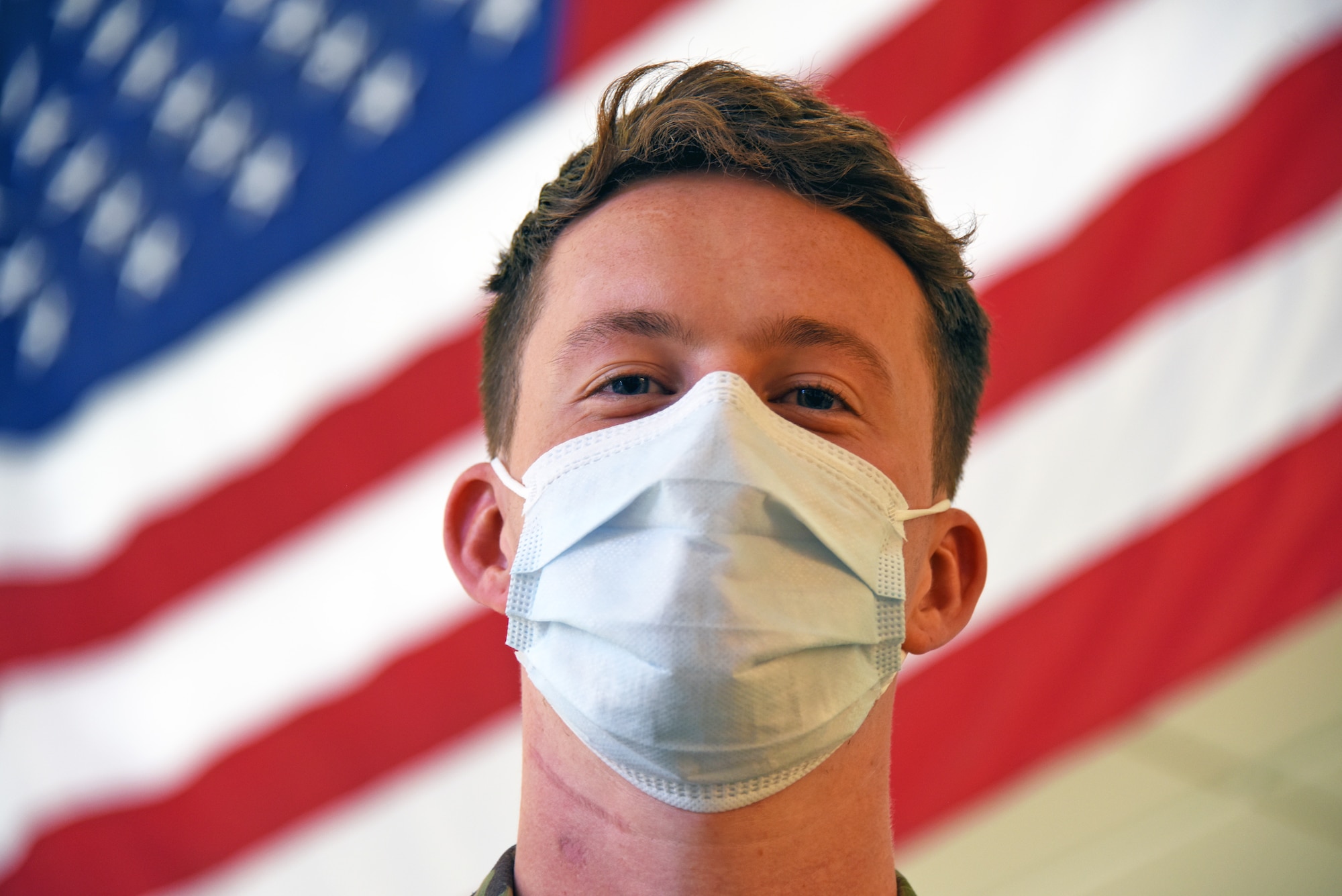 Airman poses for a picture in front of U.S. flag.