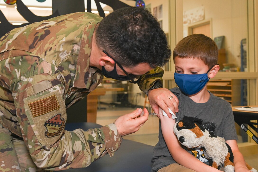 A young boy holding his stuffed animal gets vaccinated.