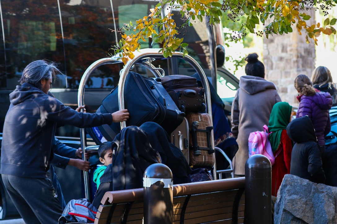 Adults and children stand together around a large amount of luggage.