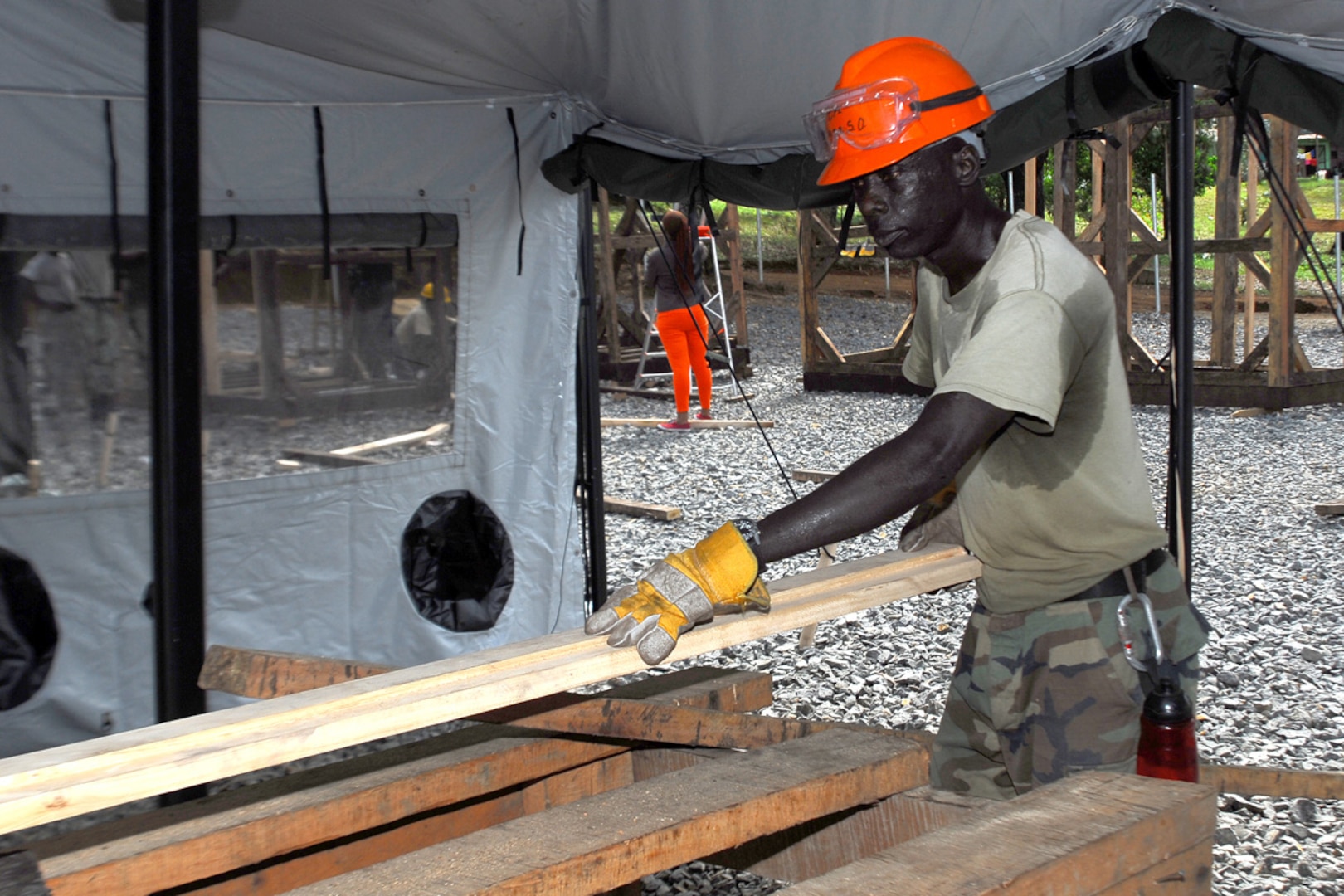 Male engineer cuts wood braces for the Tubmanburg Ebola treatment unit