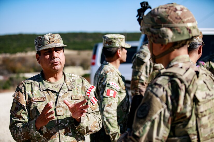 Brig. Gen. Carlos E. Bojorquez, left, 1st Multipurpose Brigade commander, Peruvian Army, talks to a U.S. Army Soldier while observing the 3rd Squadron, 3rd Cavalry Regiment conduct a platoon-level live fire and litter carry exercise at Fort Hood, Texas, Nov. 17, 2021. U.S. Army South Security Cooperation Directorate personnel escorted the Peruvian Army delegation to Fort Hood to observe U.S. Army Stryker units as part of an agreed-to-action deriving from the U.S.-Peruvian Army-to-Army Staff Talks. Army South is committed to supporting the efforts of partner nations to increase institutional capacity and regional collaboration. (U.S. Army photo by. Staff Sgt. Daniel Herman)