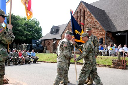 Col. John Muller, outgoing commander, 90th Troop Command, Oklahoma Army National Guard, relinquishes command to Col. Thomas Mancino during a change of command ceremony at the 45th Infantry Division Museum in Oklahoma City, Oklahoma, July 14, 2018. The passing of the 90th TC colors symbolizes the transfer of authority and responsibility from one commanding officer to another. (U.S. Army National Guard photo by Staff Sgt. Mireille Merilice-Roberts)
