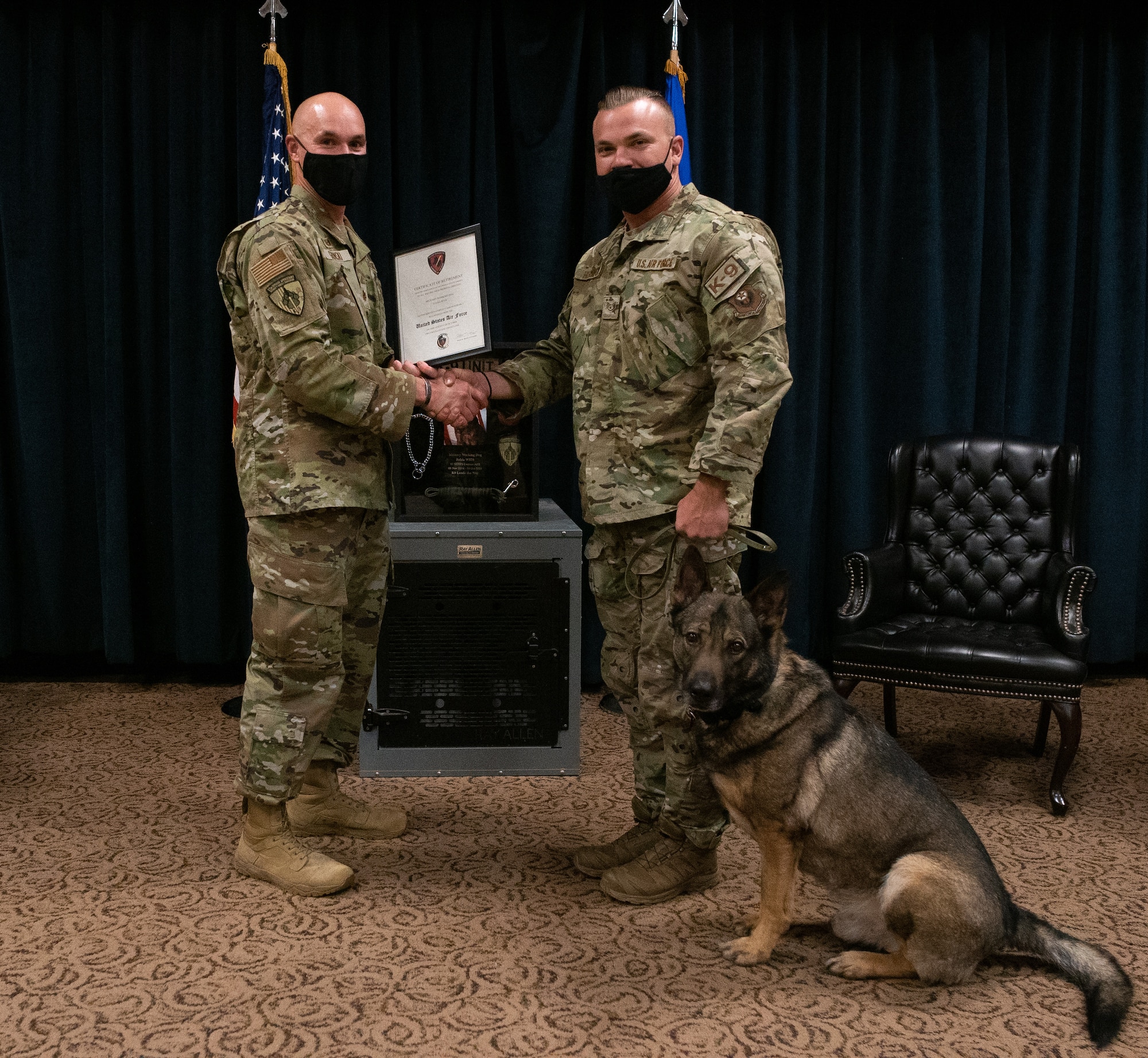 U.S. Air Force Maj. Harlan Glinski, 27th Special Operations Security Forces Squadron commander, presents a certificate of retirement to Military Working Dog Fulda W378, 27 SOSFS K-9 and his handler and adopter U.S. Air Force Staff Sgt. Michael Herman, 27 SOSFS K-9 handler at Fulda’s retirement ceremony on Cannon AFB, N.M., Nov 16, 2021. The dedication of MWD’s to their duties is deserving of an official retirement ceremony, as they play a monumental role in the safety of service members at home and down range. (U.S. Air Force photo by Senior Airman Christopher Storer)