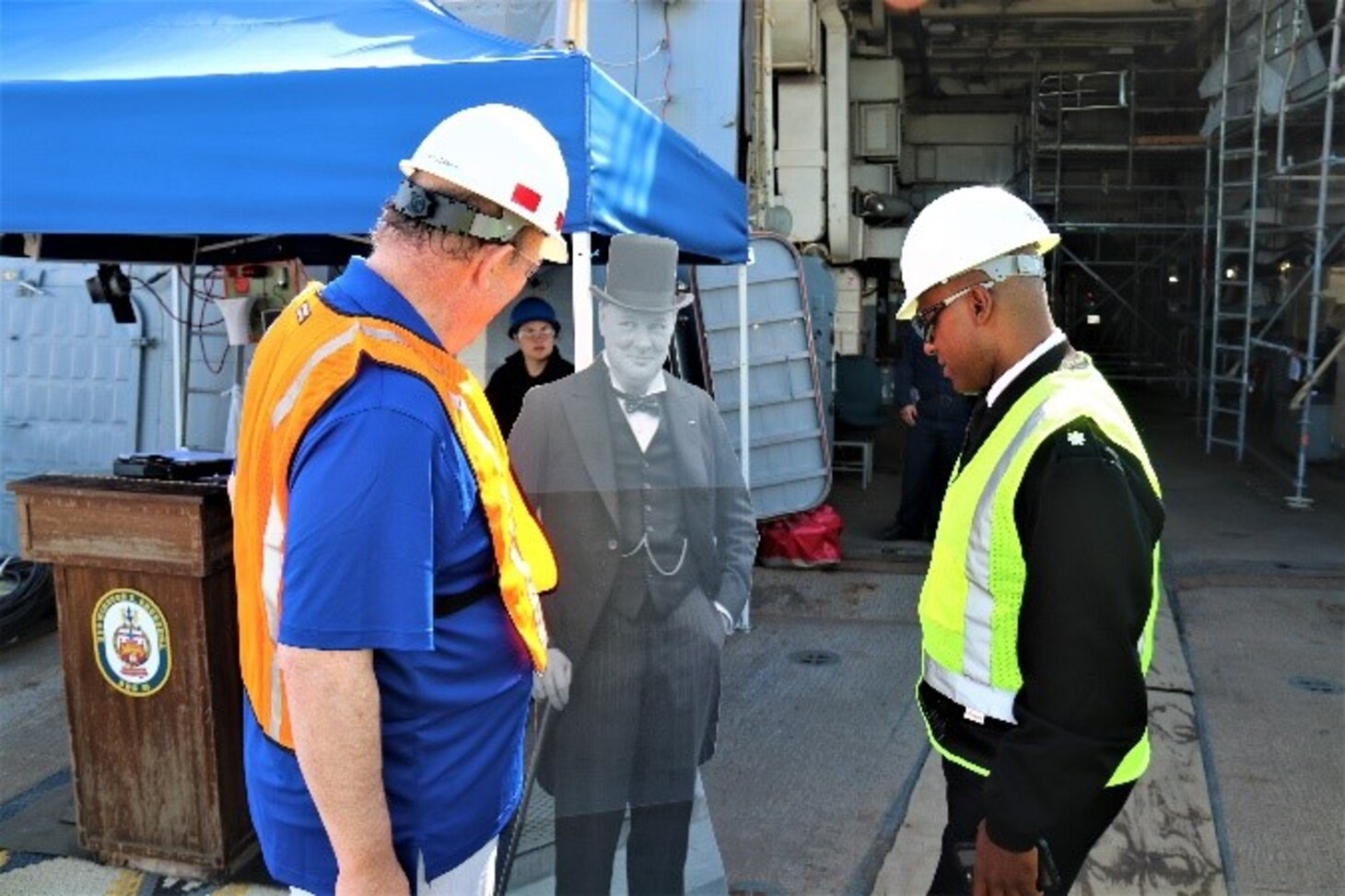 The Hon. Rupert Soames, OBE, and Cmdr. Brian Anthony, commanding officer, USS Winston S. Churchill, behold the cardboard cutout of Sir Winston Churchill, the ship’s namesake, who has graced many command photos on USS Winston S. Churchill’s Facebook page.