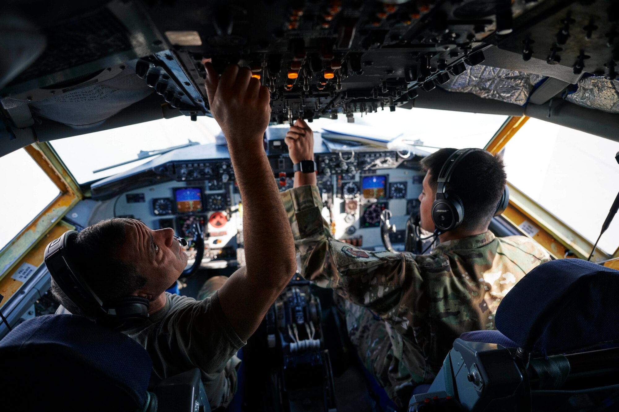 Photo of two U.S. Air Force KC-135 Stratotanker pilots performing pre-flight checks in the aircraft cockpit.