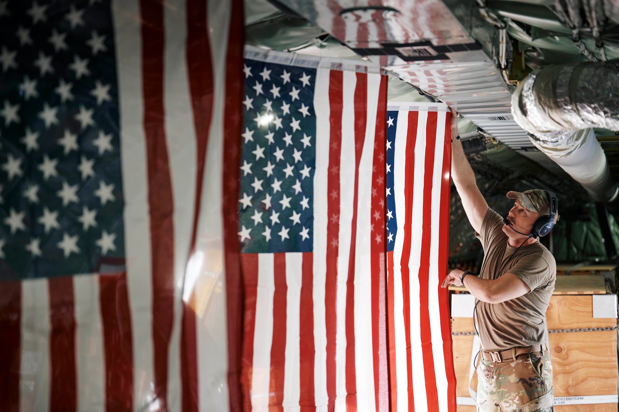 A U.S. Air Force KC-135 Stratotanker refueling specialist hangs U.S. flags inside the aircraft cabin before an aerial refueling mission.