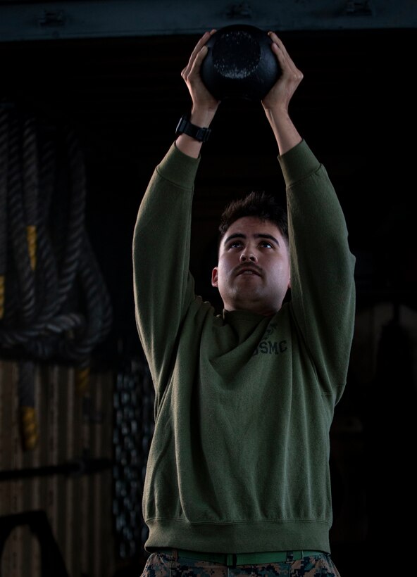 U.S. Marine Corps Lance Cpl. Hunter Barber, a combat graphics specialist with Communication Strategy and Operations, Combat Logistics Regiment 37, 3rd Marine Logistics Group, conducts kettlebell exercises on Camp Kinser, Okinawa, Japan, Nov. 17, 2021. Barber is a White Mountain Apache tribal member who grew up on the Fort Apache reservation in Arizona. "Resilient and Enduring: We Are Native People" is the November 2021 theme to honor the past and present Native American Marines who continue to pave the way for future generations. (U.S. Marine Corps photo by Cpl. Karis Mattingly)