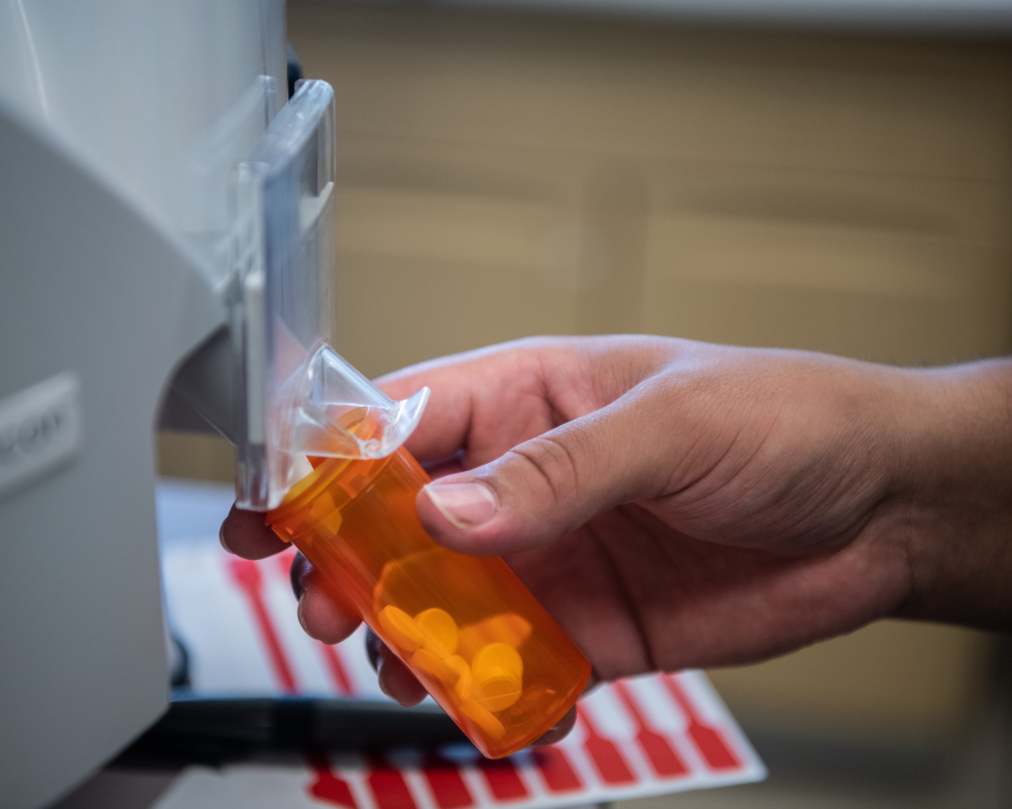 A close up of a pharmacy technician filling a bottle with pills