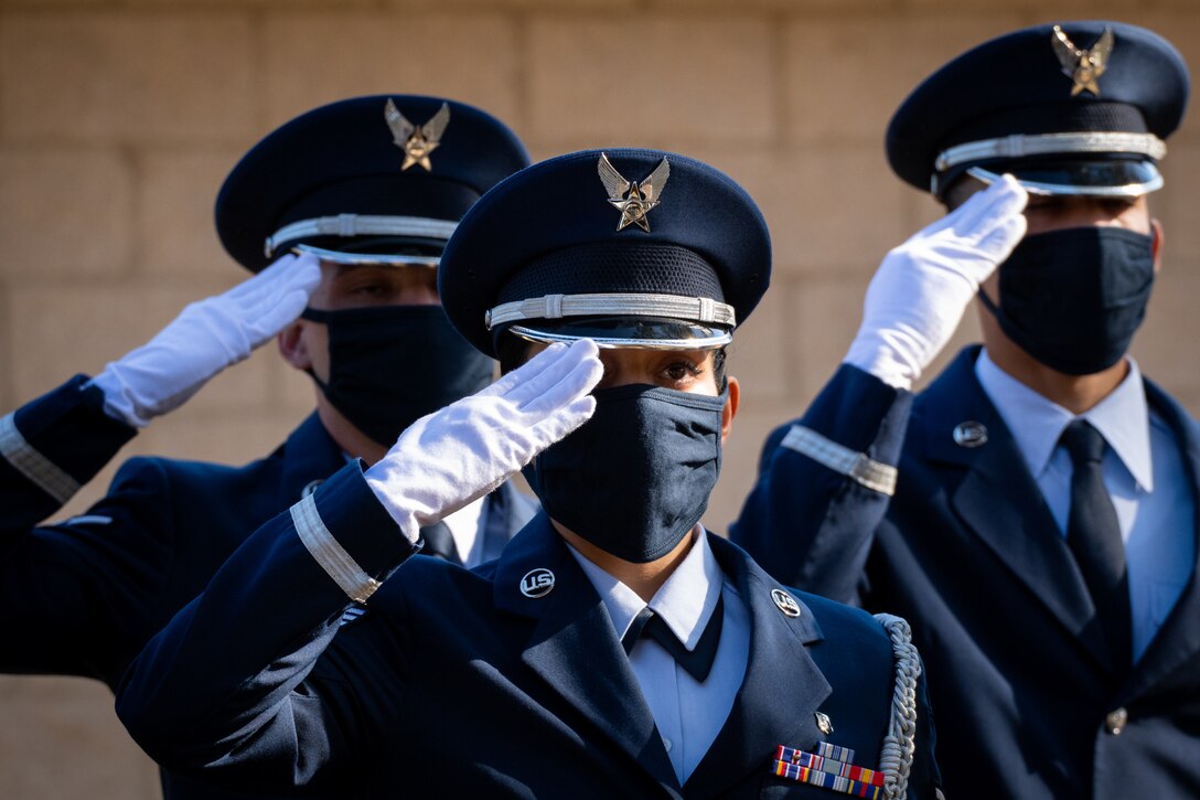 Three airmen in dress uniforms salute.