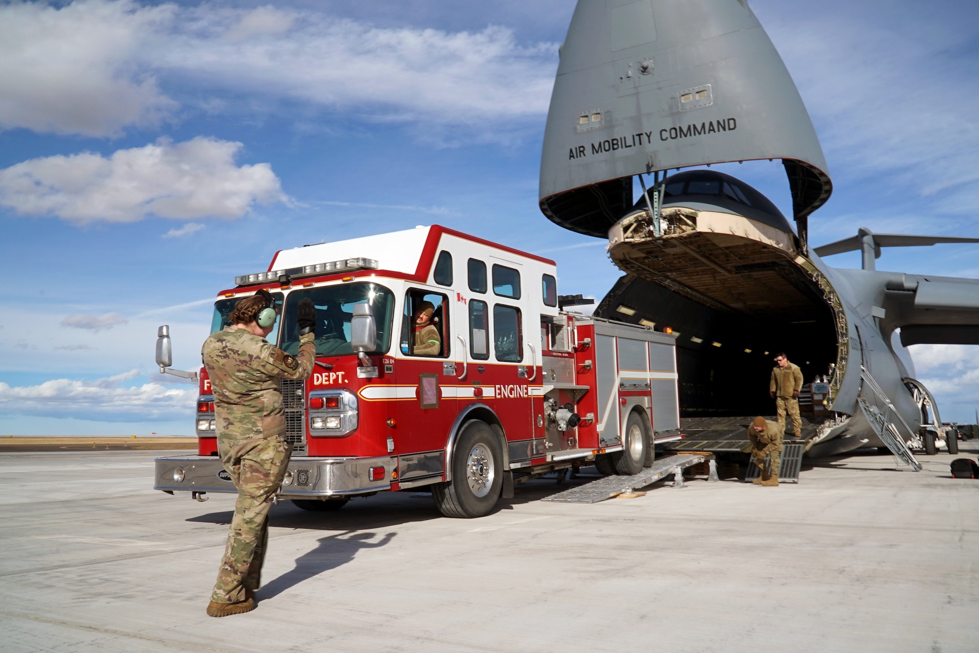 Airmen load three fire trucks onto the C-5