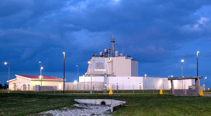 A military radar complex sits under a cloud-darkened sky.