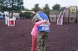 A service member assigned to Task Force Liberty embraces an Afghan child at a park at Liberty Village as she supports Operation Allies Welcome on Joint Base McGuire-Dix-Lakehurst, New Jersey, Oct. 28, 2021. The Department of Defense, through U.S. Northern Command, and in support of the Department of Homeland Security, is providing transportation, temporary housing, medical screening and general support for at least 50,000 Afghan evacuees at suitable facilities in permanent or temporary structures as quickly as possible. This initiative provides Afghan personnel essential support at secure locations outside of Afghanistan. (U.S. Air National Guard photo by Lt. Col. Candis Olmstead)