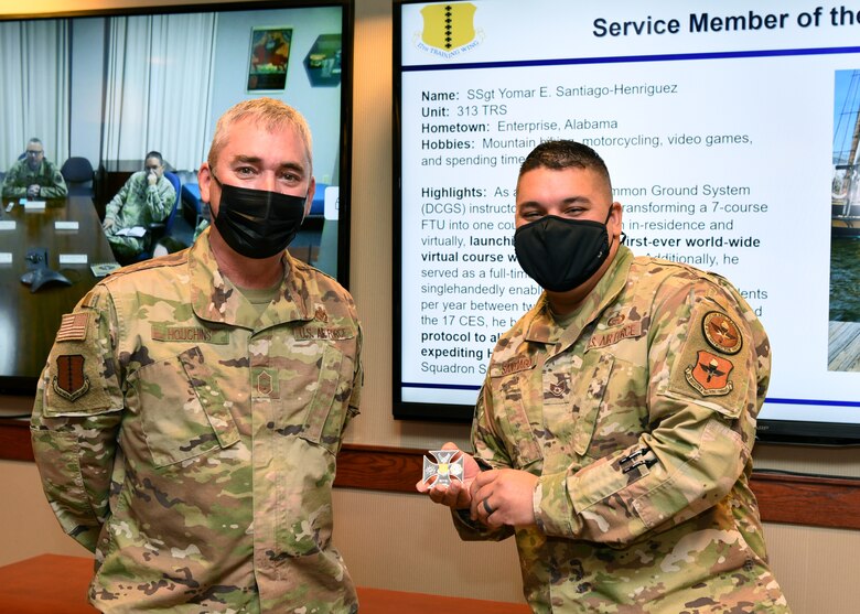 U.S. Air Force Chief Master Sgt. Craig Houchins, 17th Mission Support Group command chief and Staff Sgt. Yomar Santiago-Henriguez, 313th Training Squadron Distributed Common Ground System course instructor, pose for a photo on Goodfellow Air force Base, Texas, Nov. 16, 2021. Santiago-Henriguez was coined for his outstanding performance as an instructor and efforts leading to the heating, ventilation and air conditioning repairs inside a sensitive compartmented information facility.  (U.S. Air Force photo by Senior Airman Abbey Rieves)