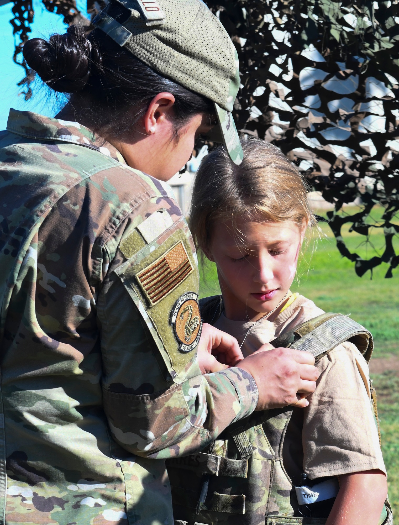 U.S. Air Force Airman 1st Class Karen Caraballo, 56th Security Forces Squadron defender, helps a military child put on protective gear during Operation Kids Investigating Deployment Services Nov. 13, 2021, at Luke Air Force Base, Arizona. Operation K.I.D.S. had similar aspects of a deployment within a simulated deployed location and included information booths with unit representatives from readiness, fire department, security forces, and aircraft maintenance.  The Airman and Family Readiness Center takes care of Airmen and their families by providing educational resources and holding events such as Operation K.I.D.S., which gives children a better understanding of their parents’ sacrifice and dedication, and allows a dialog within families about deployments. (U.S. Air Force photo by Tech. Sgt. Amber Carter)
