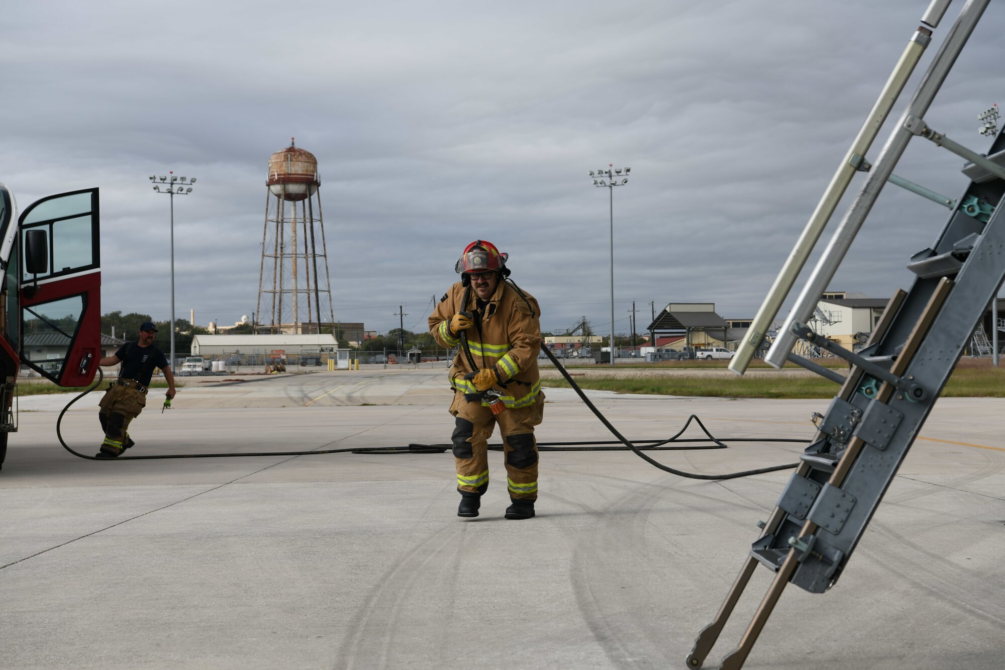 Rosendo Soto, 902nd Civil Engineer Squadron lead firefighter, pulls a water hose as he prepares to enter a 433rd Airlift Wing C-5M Super Galaxy during an emergency response exercise Nov. 15, 2021, at Joint Base San Antonio-Lackland, Texas. The event was designed to familiarize new firefighters on C-5 procedures and provide refresher training for seasoned team members. (U.S. Air Force photo by Master Sgt. Kristian Carter)