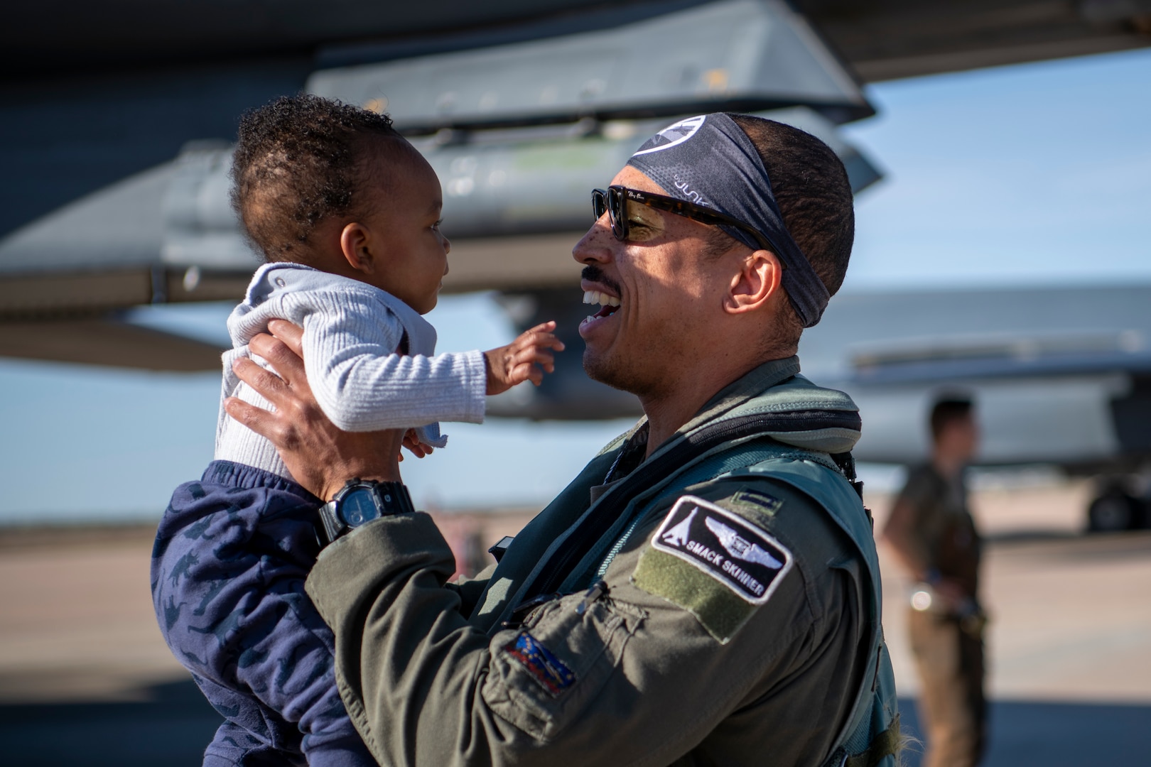 Capt. Malcolm Skinner, 9th Bomb Squadron weapons system officer, holds his child after returning to Dyess Air Force Base, Texas, Nov. 14, 2021, from a Bomber Task Force Europe deployment.