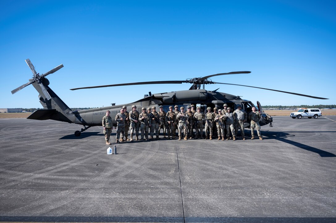 Airmen pose in front of a U.S. Army UH-60 Blackhawk for a photo.
