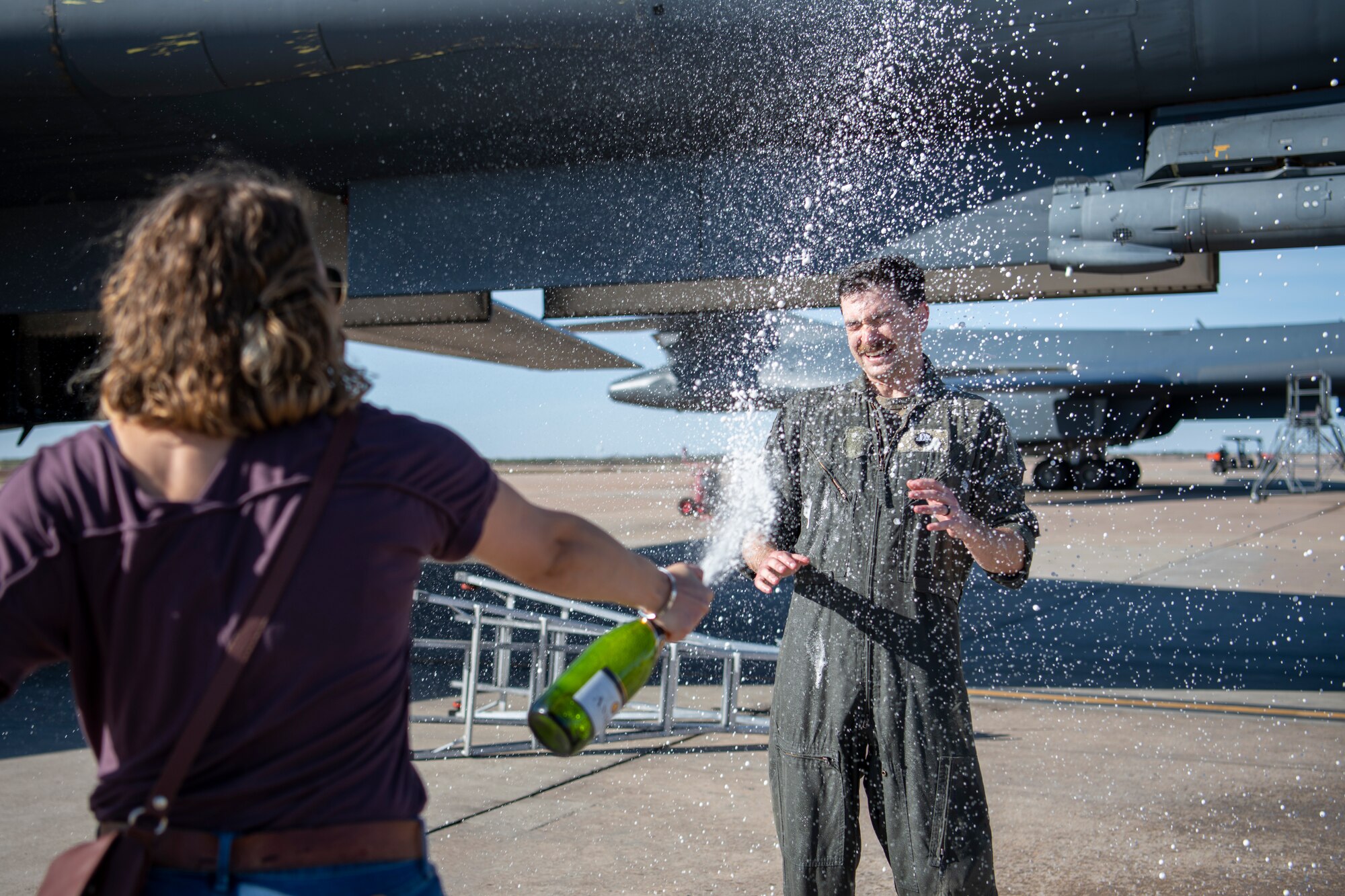 Capt. Eric Hickok, 9th Bomb Squadron pilot, is sprayed with champagne by his spouse after returning home on his last flight to Dyess Air Force Base, Texas, Nov. 14, 2021, from a Bomber Task Force Europe deployment.