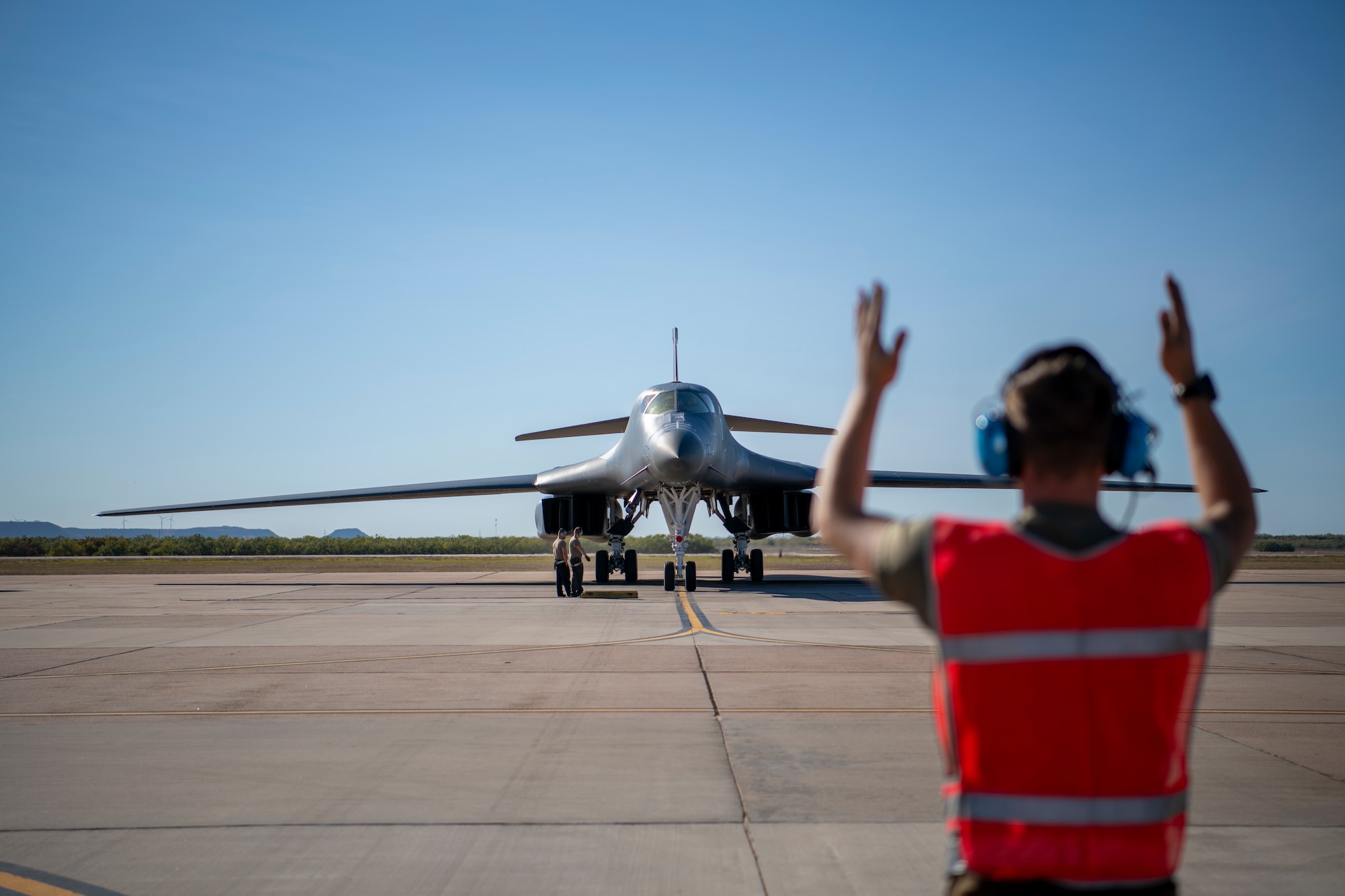 Airman 1st Class Coby Delia, 9th Aircraft Maintenance Unit crew chief, marshals a B-1B Lancer onto the flightline at Dyess Air Force Base, Texas, Nov. 14, 2021.