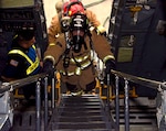 Jake Spalding and Leonard Gerlich, 902nd Civil Engineer Squadron firefighters, ascend stairs leading to a C-5M Super Galaxy flight deck to check for simulated incapacitated aircrew members during an exercise Nov. 18, 2021, at Joint Base San Antonio-Lackland, Texas. During the event, firefighters simulated extinguishing a main landing gear brake fire and assisting the aircrew with evacuating the aircraft. (U.S. Air Force photo by Samantha Mathison)