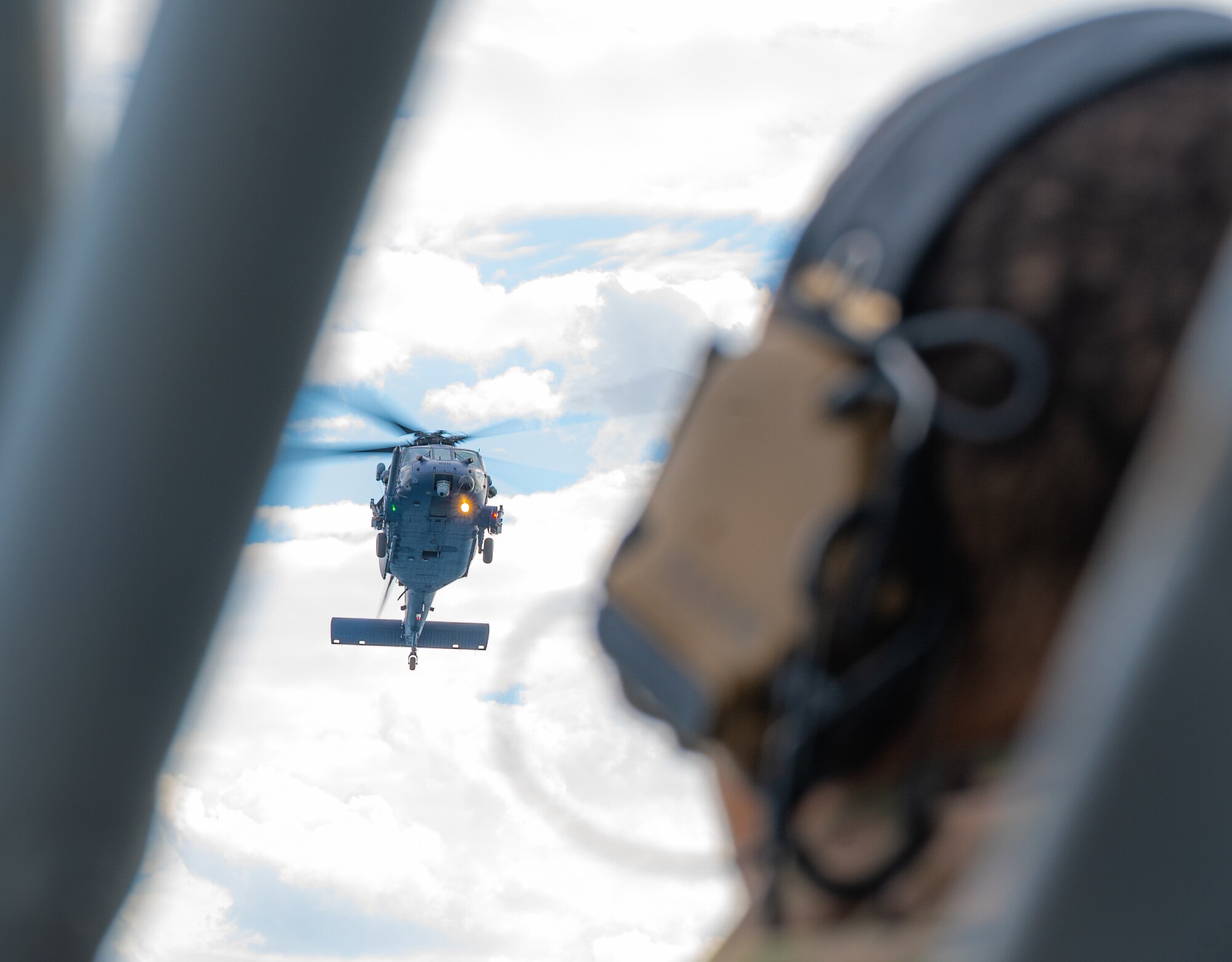 An Airman observes a helicopter fly.