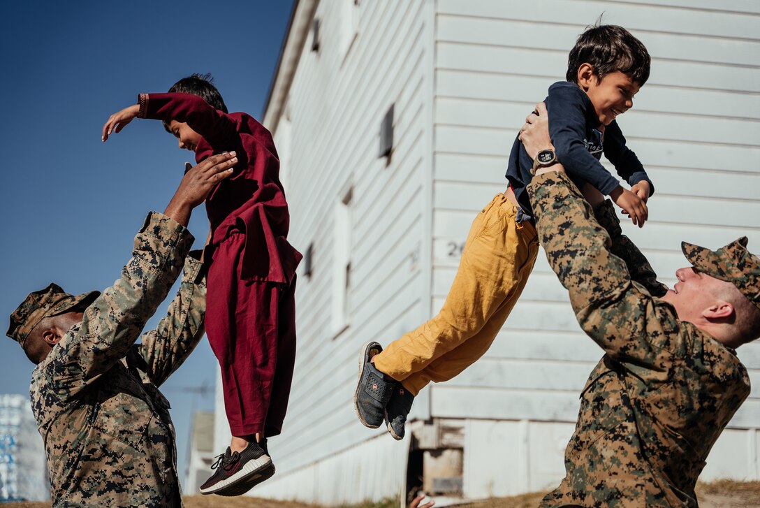 U.S. Marine Corps Cpl. Christophe Strickland (Left), and Cpl. Ethan Gentry (Right), both mortarmen with 1st Battalion, 23rd Marine Regiment (1/23), play with Afghan children on Fort Pickett, Virginia, Nov. 18, 2021.
