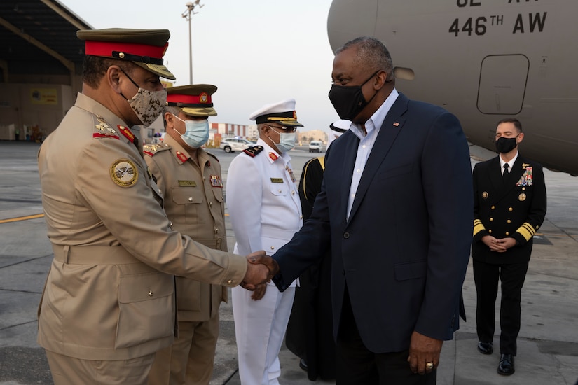 Two men, one in a military uniform, shake hands.