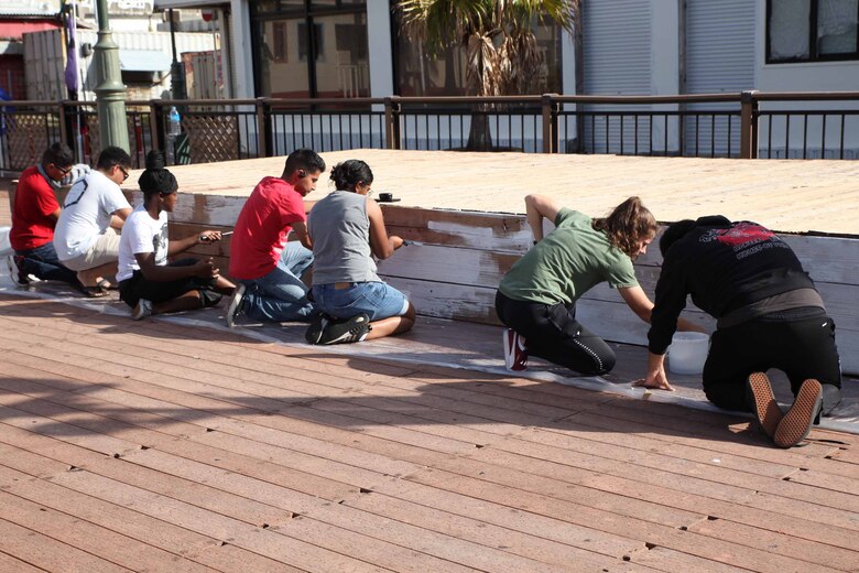 金武町新開地地区の中心に位置するアクティブパークにあるステージにシーラー塗装を使って下塗りをする海兵隊員たち、沖縄県金武町、2021年11月20日