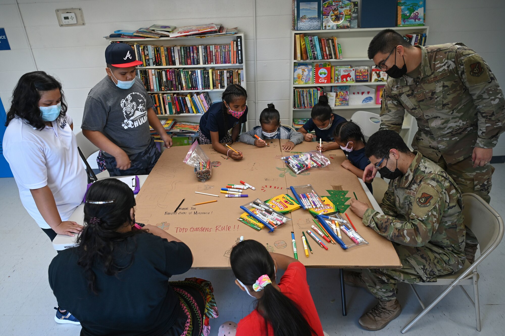 Children with Mañe'lu, U.S. Air Force Airman 1st Class Lijie Lu, budget analysis with 36th Comptroller Squadron, and A1C Joshua Thompson, a budget analysis with 36 CPTS, draw and write messages on a box during a volunteer event at Toto Garden, Mongmong-Toto-Maite, Nov. 18th, 2021. The two Airmen from 36th CPTS volunteered through Andersen Air Force Base’s Sister Village Sister Squadron program and joined the children with Mañe'lu to decorate boxes that will be used during Operation Christmas Drop with donated supplies. (U.S. Air Force photo by Senior Airman Aubree Owens)