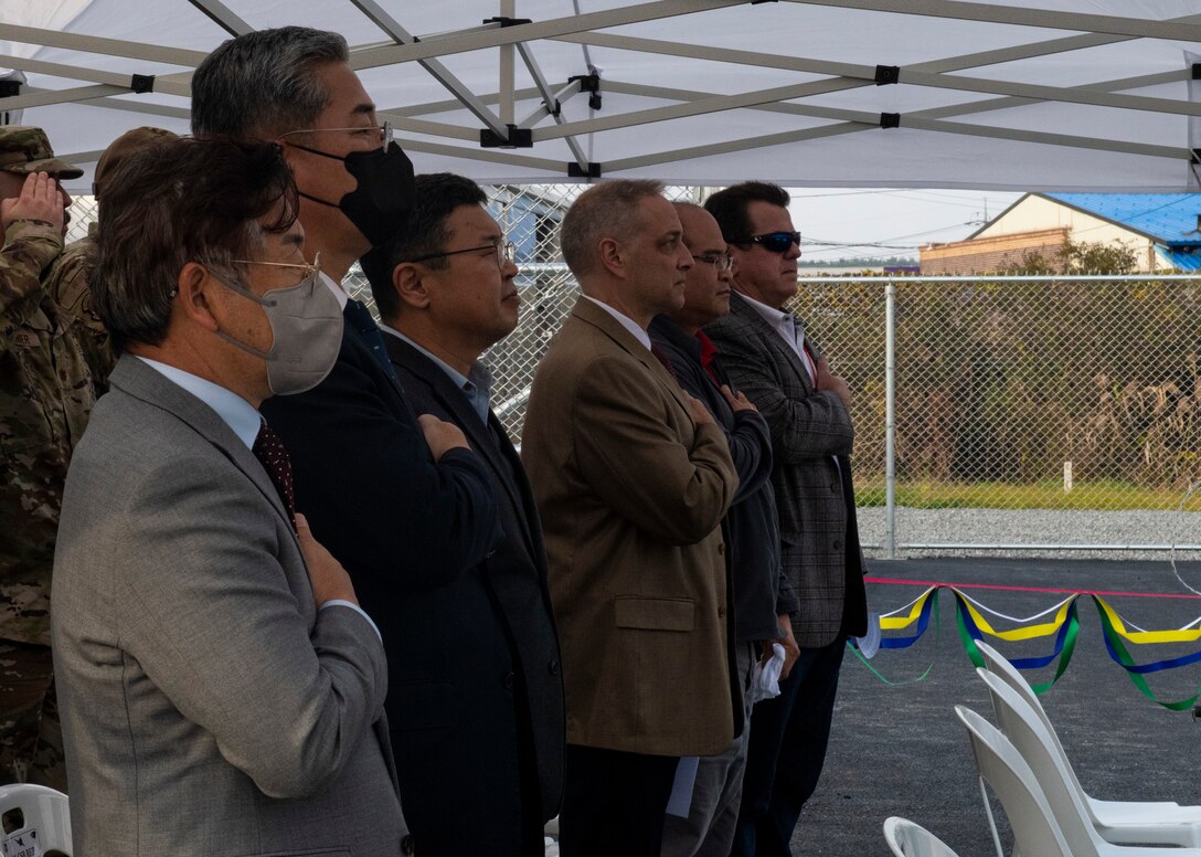 Kunsan mission partners and members from Honeywell place their hands over their hearts while the National Anthem plays during the installation’s Natural Gas Pipeline Ribbon Cutting Ceremony at Kunsan Air Base, Republic of Korea, Nov. 15, 2021. The natural gas pipeline was installed to provide reliable, sustainable and energy-efficient heating to buildings on the installation. (U.S. Air Force photo by Staff Sgt. Suzie Plotnikov)