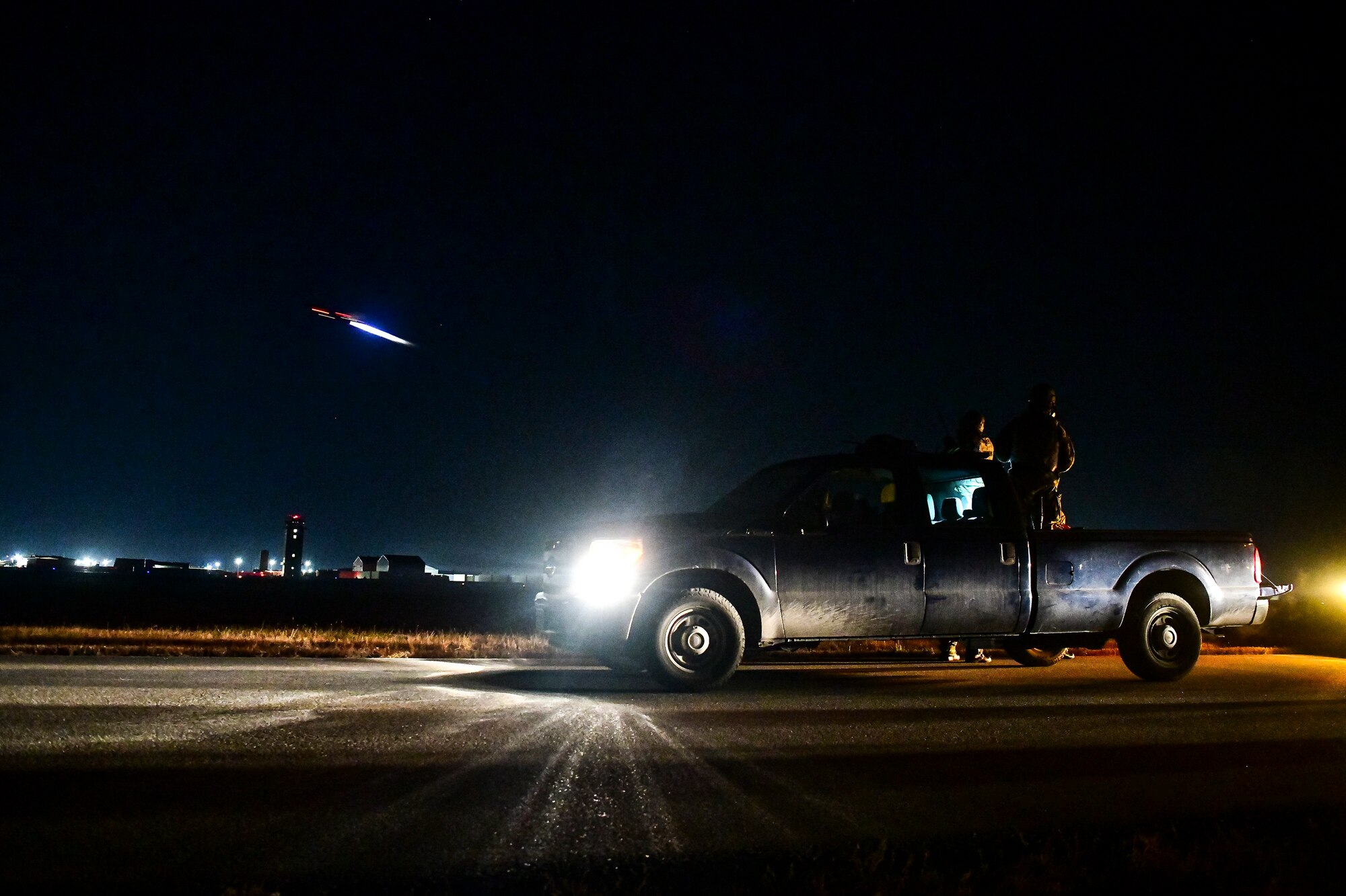 Airmen watch an F-16 fly by.
