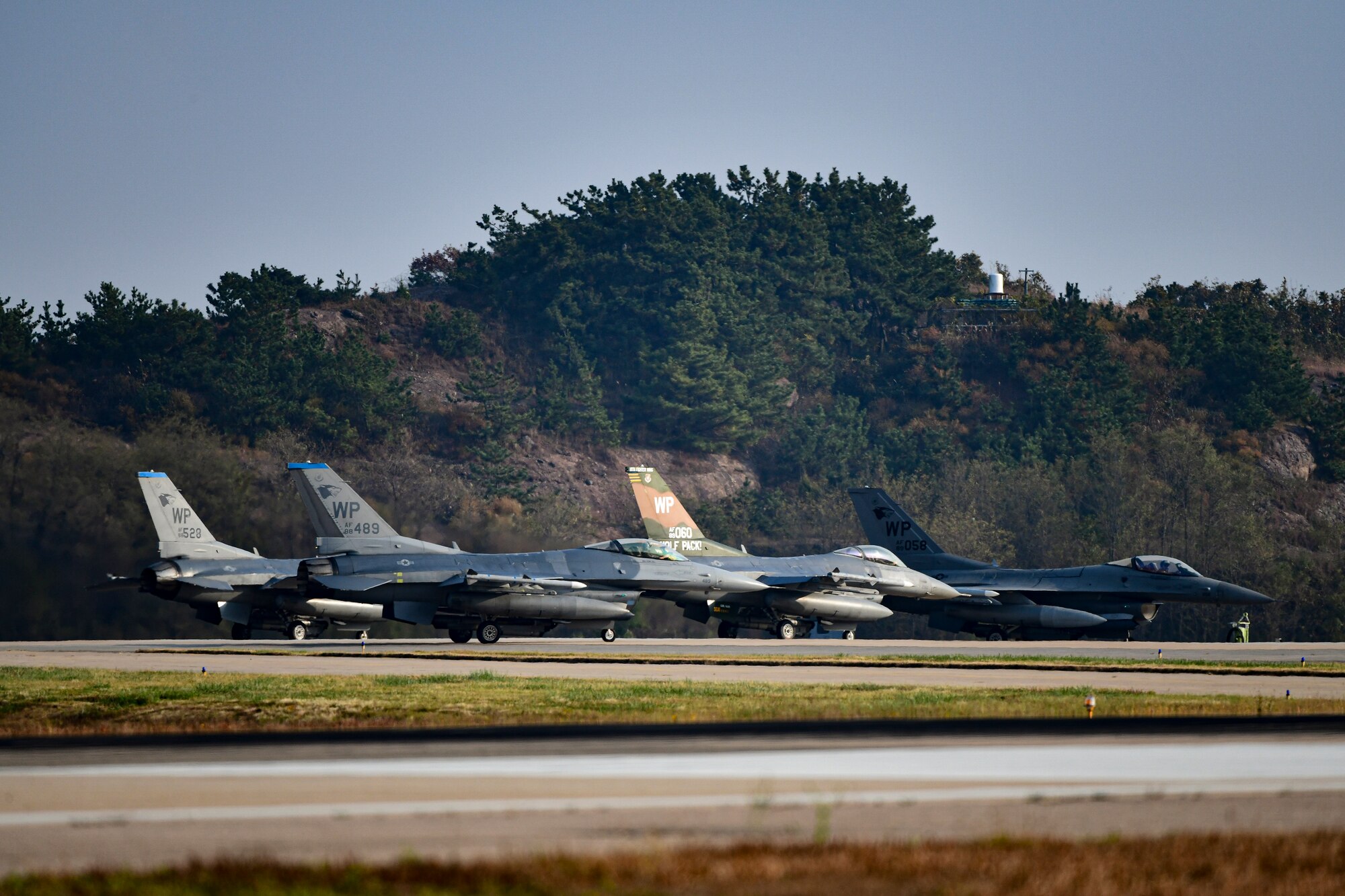 Fighter jets park on the runway.