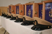 211119-N-GW139-1048 NAVAL SUPPORT ACTIVITY NAPLES, Italy (Nov. 19, 2021) Covers and vessels line the stage of a Chief Petty Officer pinning ceremony onboard U.S. Naval Support Activity Naples (NSA), Nov. 19, 2021. NSA Naples is an operational ashore base that enable U.S., allied, and partner nation forces to be where they are needed, when they are needed to ensure security and stability in Europe, Africa, and Southwest Asia. (U.S. Navy Photo by Mass Communication Specialist 1st Class Eric Coffer)