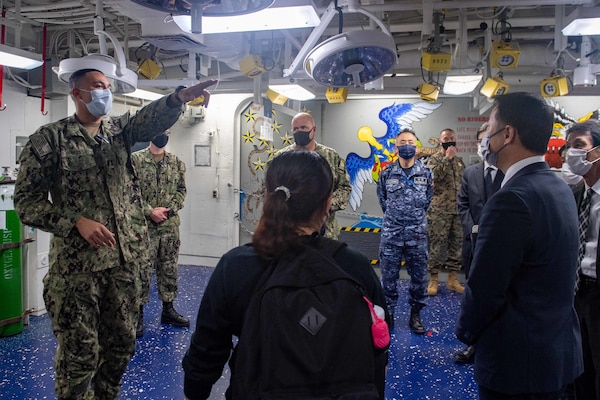 Lt. Paul Moss, the general medical officer aboard the forward-deployed amphibious assault ship USS America (LHA 6), conducts a tour of the ship’s medical facility for local and regional civic and military leadership during a port visit to Marine Corps Air Station Iwakuni. America, lead ship of the America Amphibious Ready Group, is operating in the U.S. 7th Fleet area of responsibility to enhance interoperability with allies and partners and serve as a ready response force to defend peace and stability in the Indo-Pacific region.