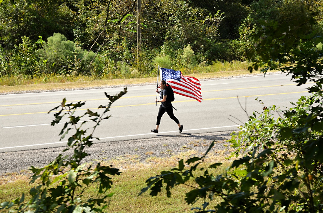 Woman runs with American flag held high in the air.