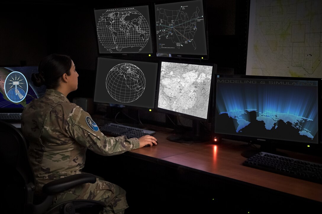 U.S. Space Force Sgt. sitting at a desk and looking at multiple computer screens