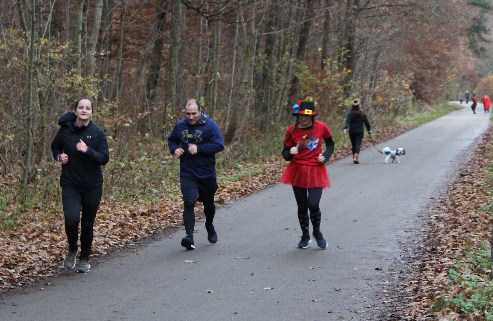 A group pf people run along a wooded path.