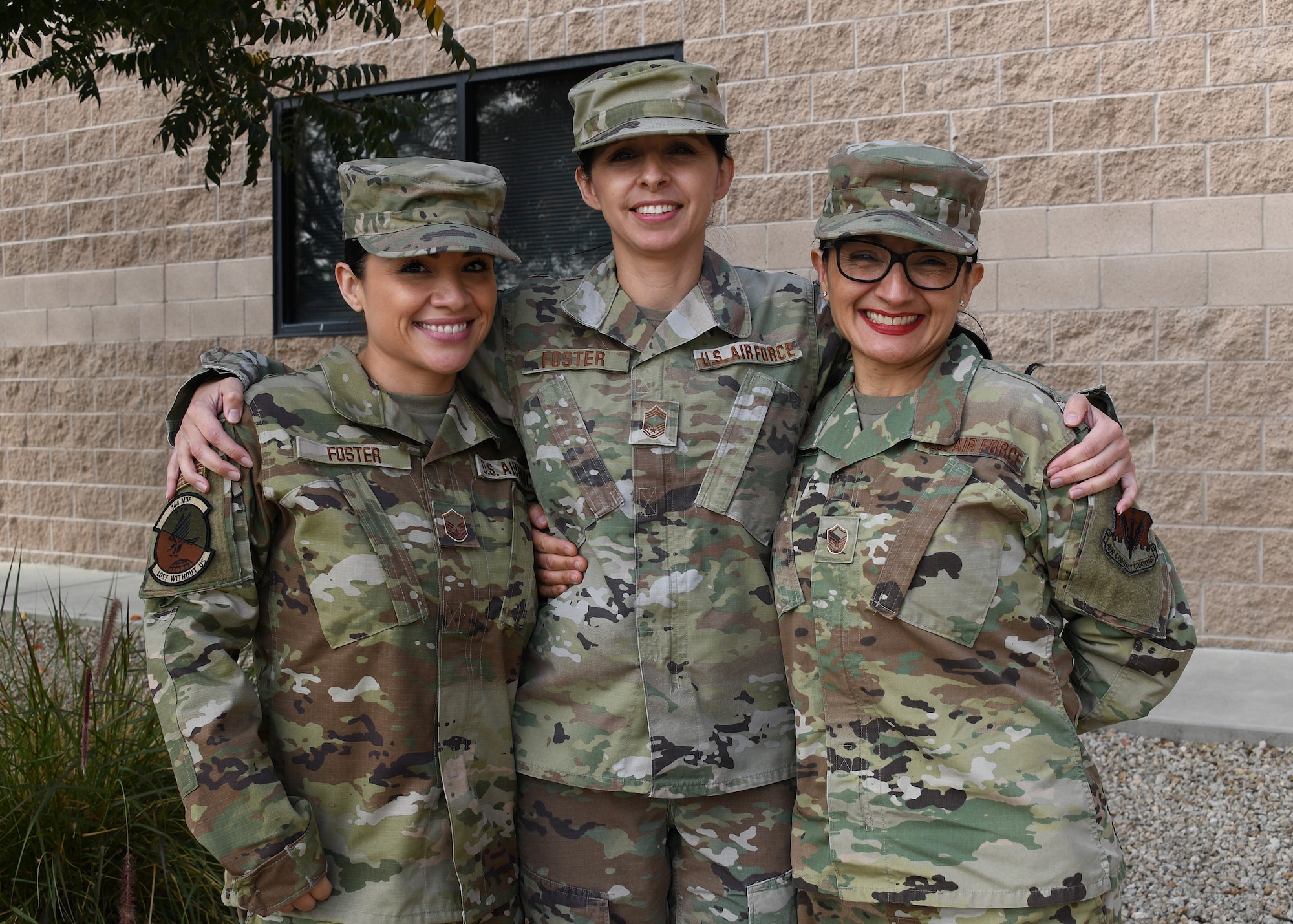 A group of three women stand side by side to each other to take a group photo.