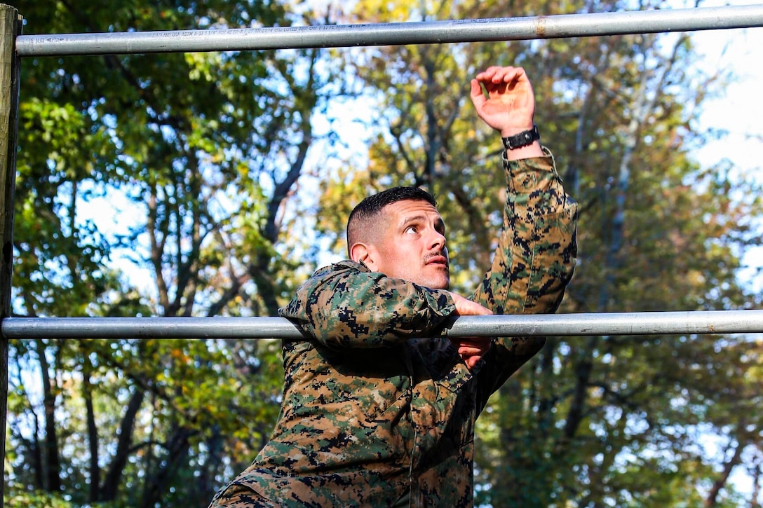 A service member climbs through an obstacle course.