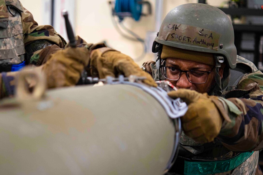 An airman looks closely at a bomb.