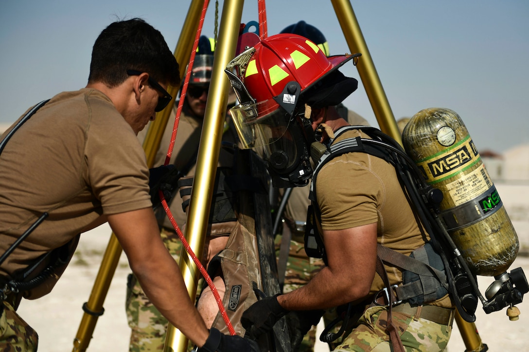 Airmen lift a simulated airman out of a hole during training.