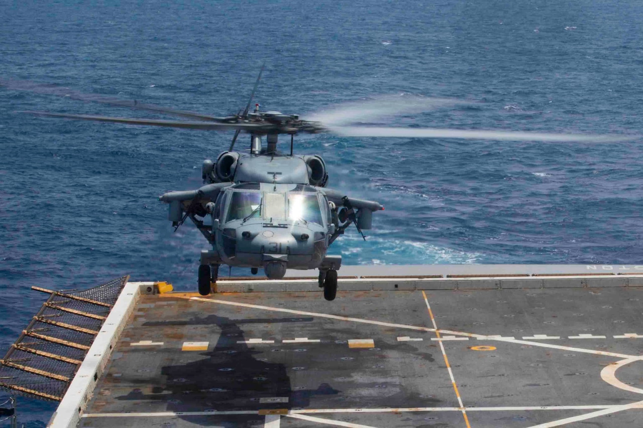 A helicopter takes off from the deck of a Navy ship.