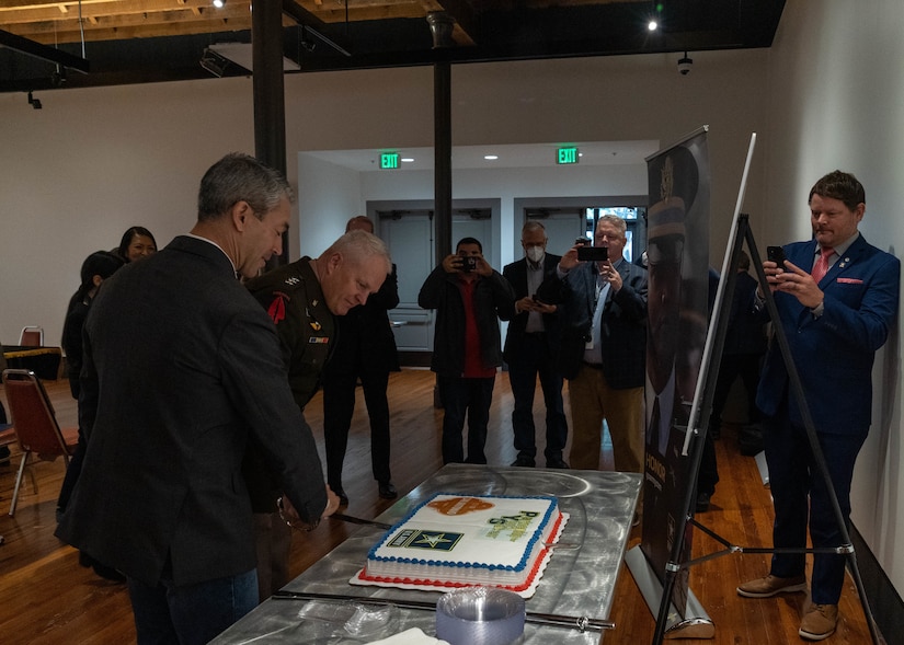 U.S. Army North Commanding General Lt. Gen. John R. Evans Jr., center, and city of San Antonio Mayor Ron Nirenberg, left,  cut a cake at the U.S. Army Partnership for Youth Success (PaYS) Singing Ceremony at the Plaza de Armas Gallery, San Antonio, Texas, Nov. 19, 2021. The U.S. Army PaYS Program guarantees Soldiers and ROTC cadets five job interviews and possible employment with the city of San Antonio government after their service in the U.S. Army.