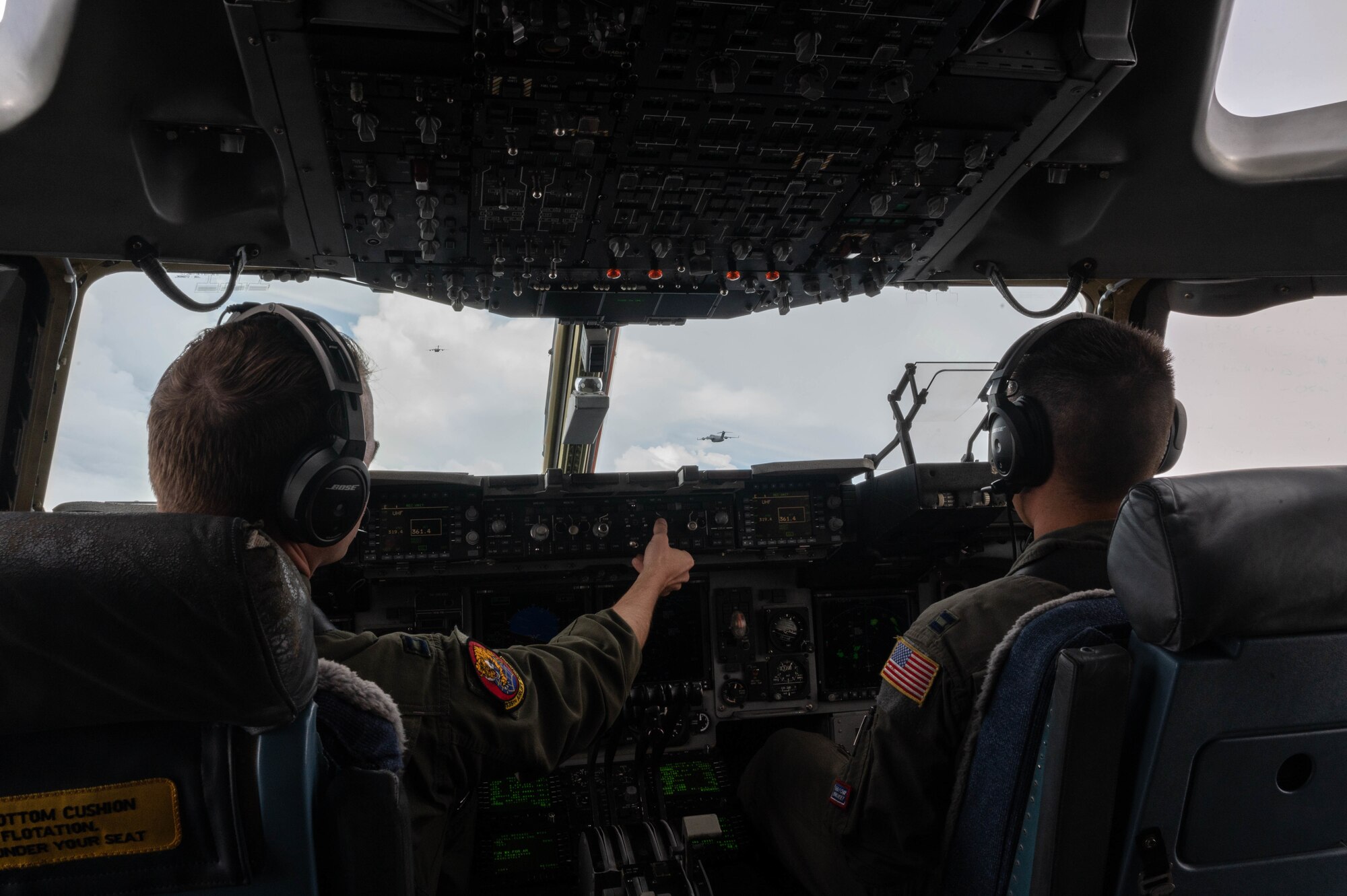 Capt. Alec Nelson, 535th Airlift Squadron C-17A Globemaster III aircraft commander, and Capt. Ken Nakanishi, 535th AS C-17 pilot, participate in a three-ship formation with Royal Australian Air Force C-17s during a training exercise over the West Pacific, Nov. 14, 2021. The United States and Australia provide security throughout the Indo-Pacific region by enhancing their mission effectiveness through integrated cooperation. (U.S. Air Force photo by Staff Sgt. Alan Ricker)