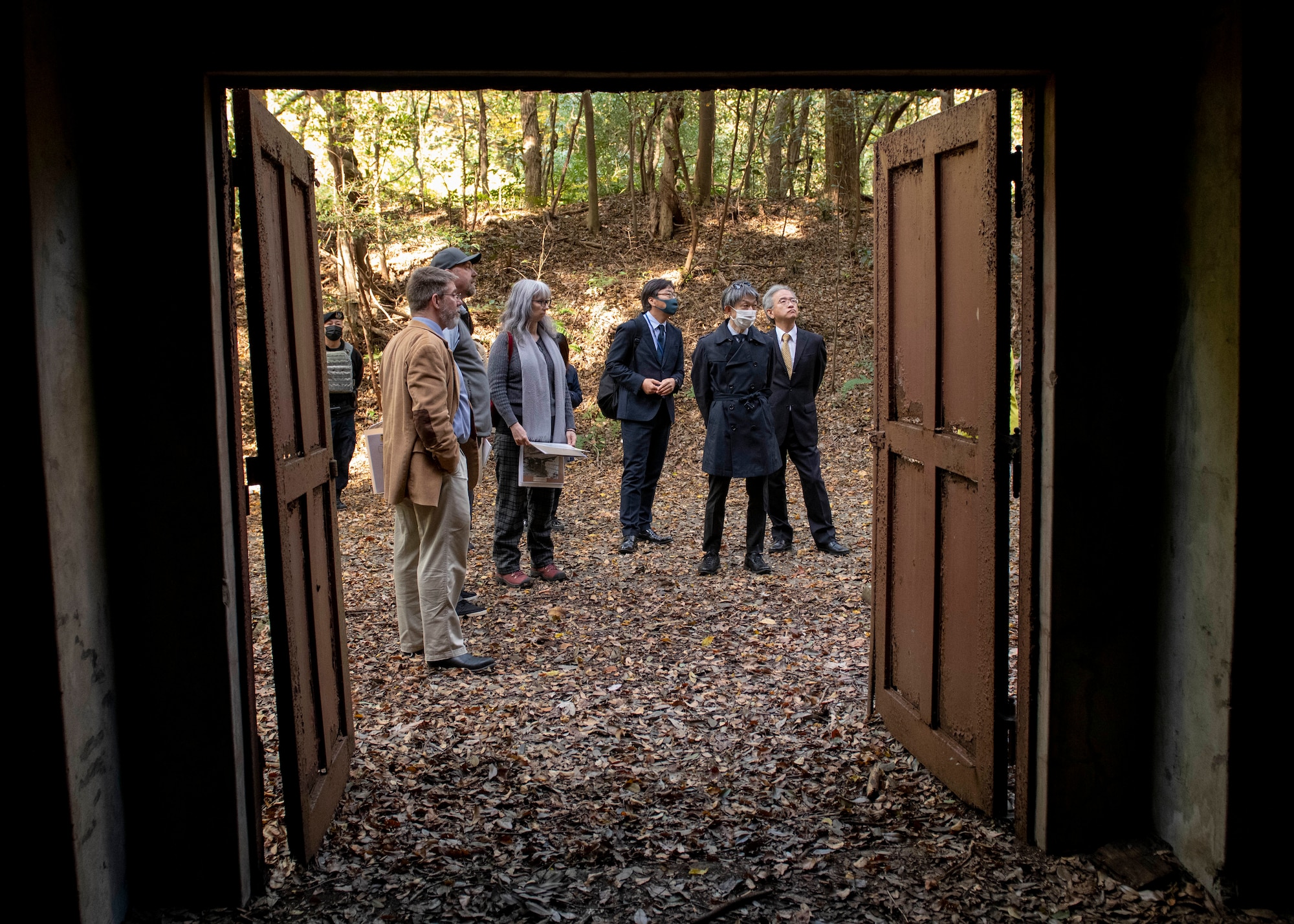 A group of U.S. Air Force and Japanese government officials stand outside a WWII era ammo storage building.