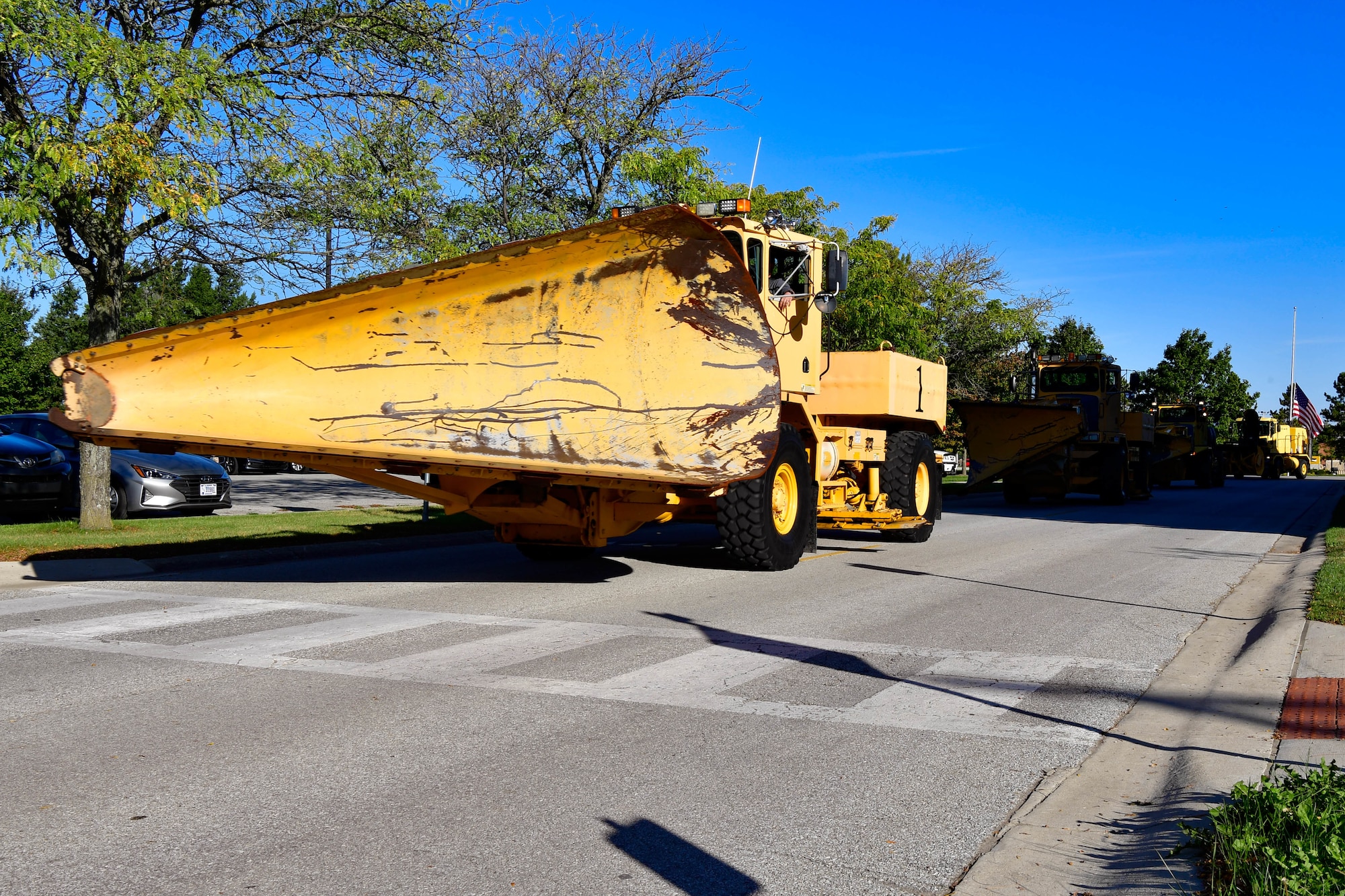 A snow plow and other snow removal equipment drive through Grissom Air Reserve Base, Indiana on Oct. 19, 2021. Grissom held a Snow Parade to inspect snow removal equipment. (U.S. Air Force photo by Staff Sgt. Jeremy Blocker)